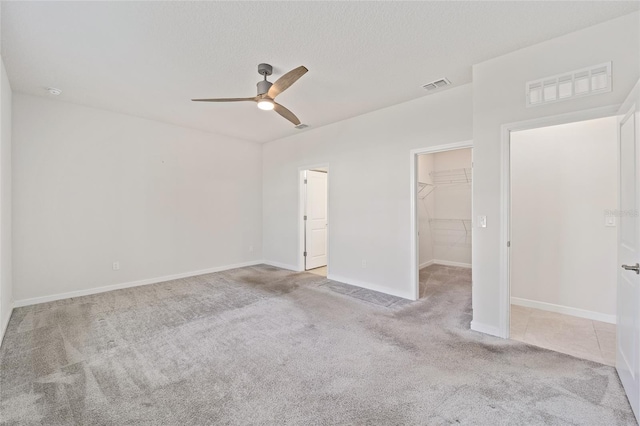 spare room with a textured ceiling, ceiling fan, and light carpet