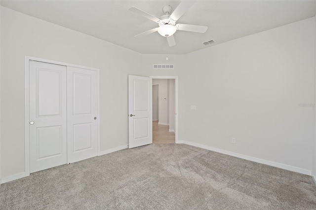 unfurnished bedroom featuring ceiling fan, a closet, and light colored carpet