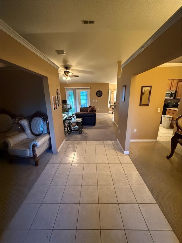 living room featuring a textured ceiling, ceiling fan, light tile patterned floors, and crown molding