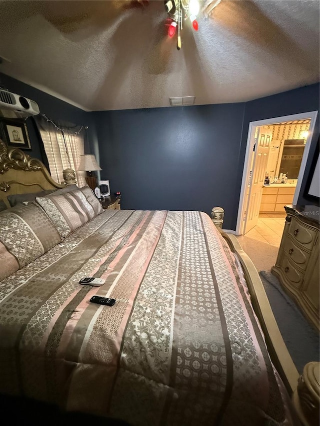 carpeted bedroom with a textured ceiling and connected bathroom