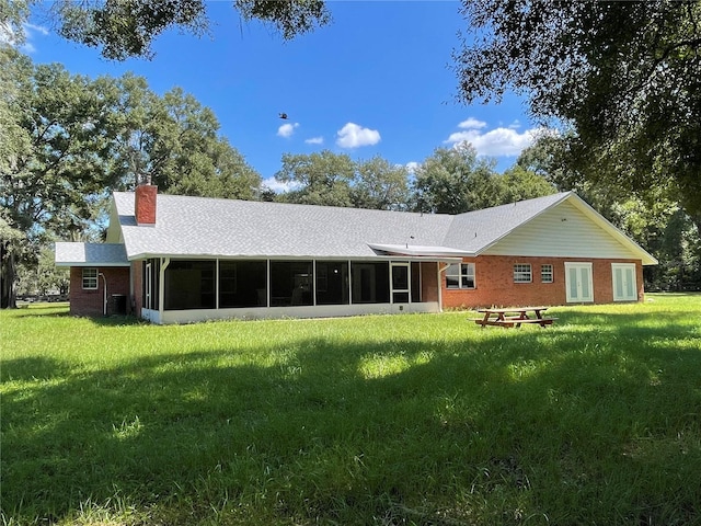 9526 SW 72nd Ct, Ocala, FL 34476 - back of property with a sunroom, a lawn, a chimney, a shingled roof, and brick siding