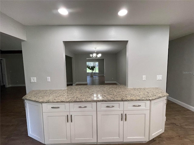 kitchen with light stone countertops, dark hardwood / wood-style flooring, and white cabinets