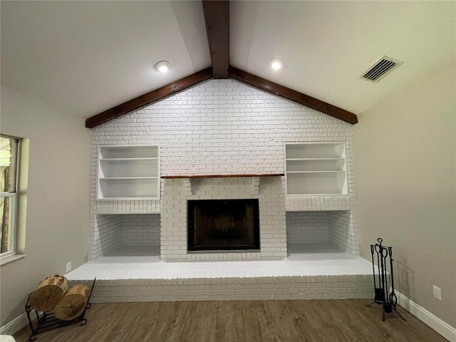 unfurnished living room with built in shelves, vaulted ceiling with beams, hardwood / wood-style flooring, and a brick fireplace