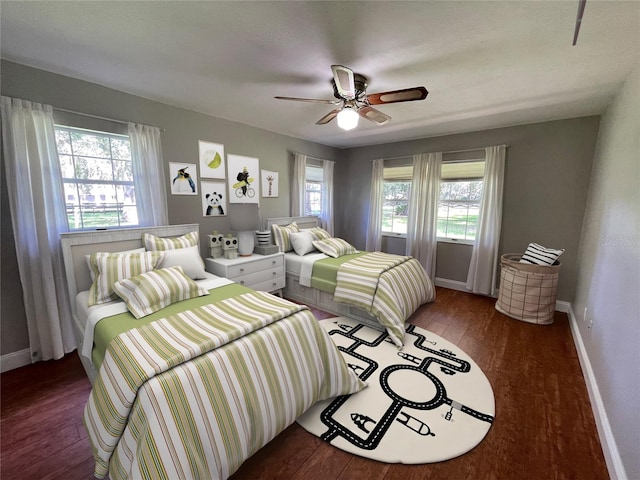 bedroom featuring ceiling fan, multiple windows, and dark hardwood / wood-style flooring