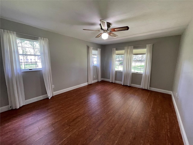 spare room with dark hardwood / wood-style floors, a wealth of natural light, and ceiling fan