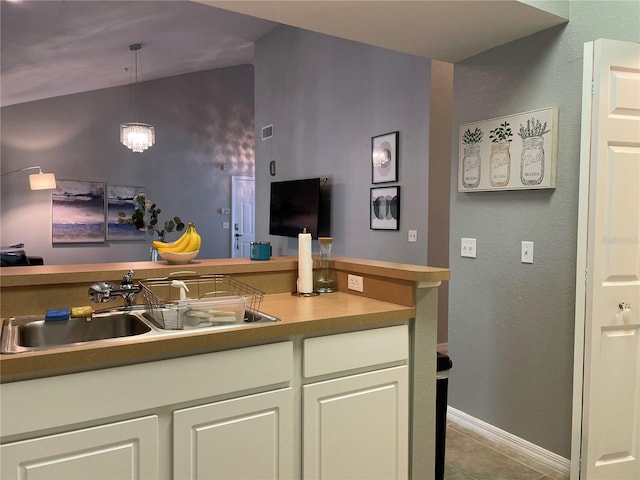 kitchen with white cabinetry, sink, light tile patterned floors, and decorative light fixtures