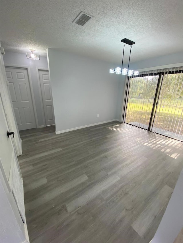 spare room featuring an inviting chandelier, a textured ceiling, and hardwood / wood-style floors