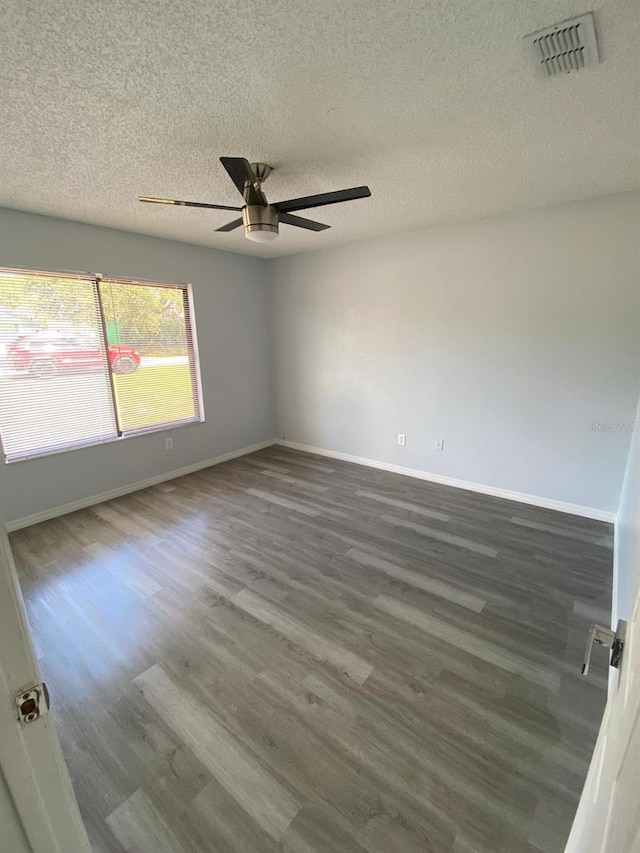 spare room featuring a textured ceiling, dark wood-type flooring, and ceiling fan