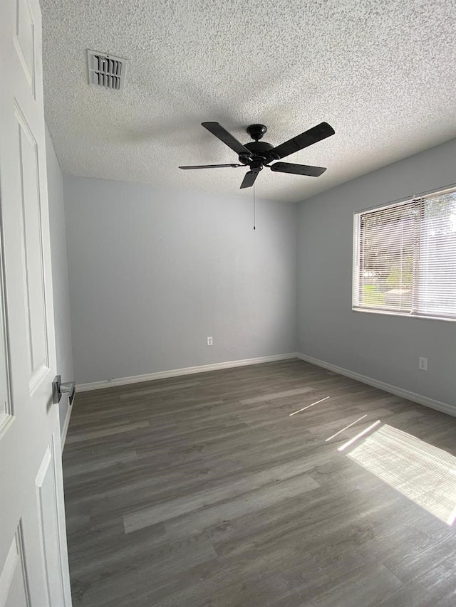 empty room featuring a textured ceiling, dark hardwood / wood-style floors, and ceiling fan