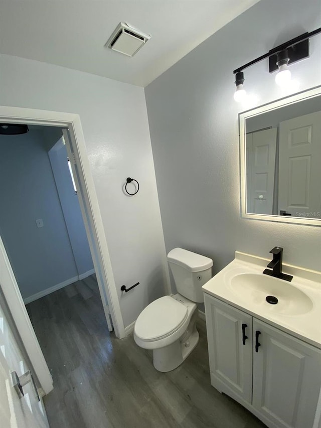 bathroom with hardwood / wood-style floors, vanity, and toilet