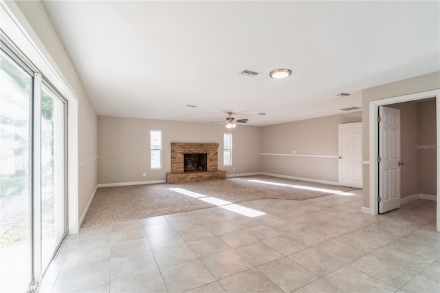 unfurnished living room with ceiling fan, light colored carpet, a fireplace, and a healthy amount of sunlight