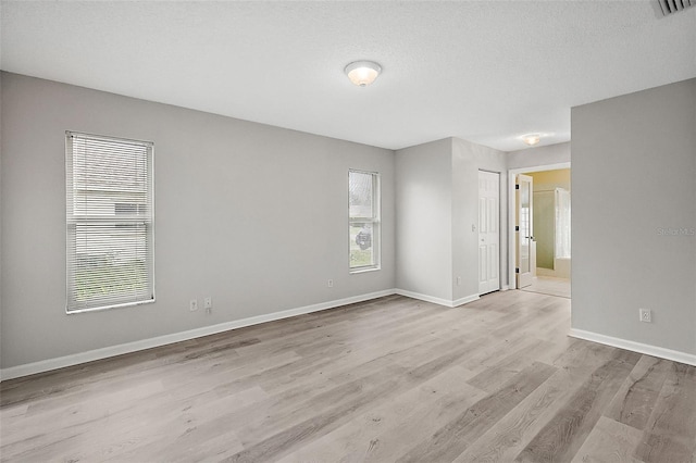 spare room featuring a textured ceiling and light hardwood / wood-style floors