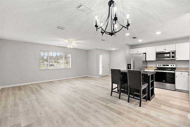 kitchen with light wood-type flooring, white cabinetry, a kitchen bar, a kitchen island, and appliances with stainless steel finishes