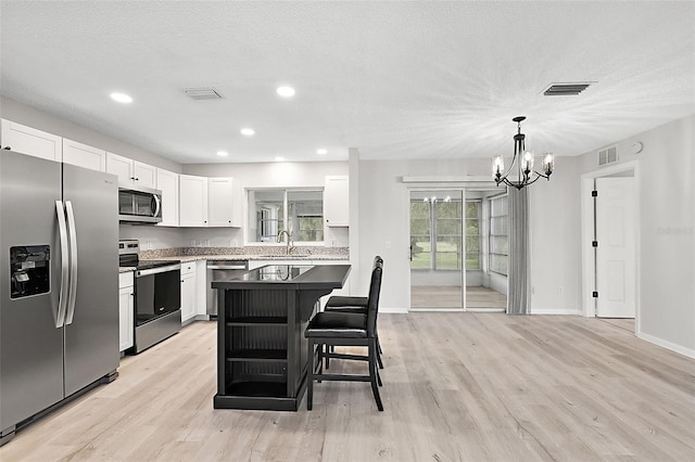 kitchen featuring white cabinets, sink, a kitchen island, light hardwood / wood-style flooring, and stainless steel appliances