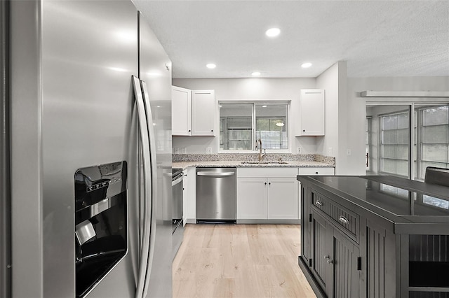 kitchen featuring light hardwood / wood-style flooring, stainless steel appliances, white cabinets, and sink