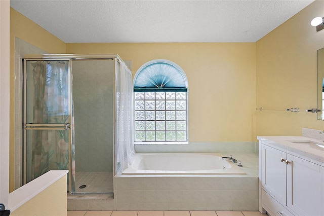 bathroom with a textured ceiling, tile patterned flooring, vanity, and plus walk in shower