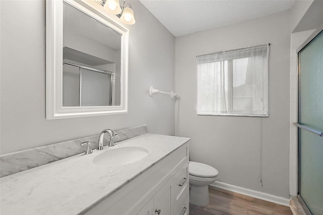 bathroom with vanity, a textured ceiling, wood-type flooring, a shower with door, and toilet