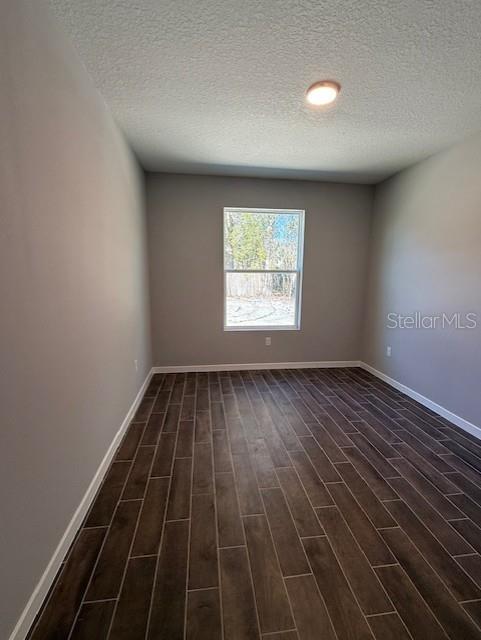 unfurnished room with dark hardwood / wood-style floors and a textured ceiling