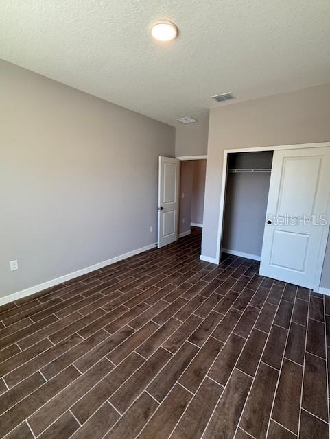 unfurnished bedroom with dark hardwood / wood-style floors, a closet, and a textured ceiling