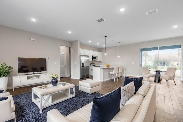 living room with recessed lighting, light wood finished floors, visible vents, and baseboards