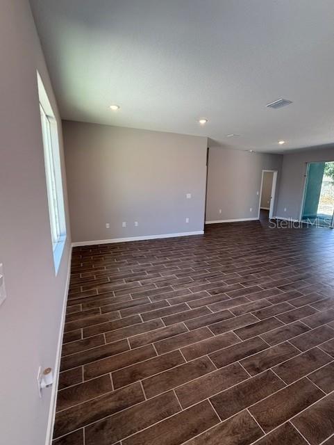 empty room with baseboards, recessed lighting, and dark wood-type flooring