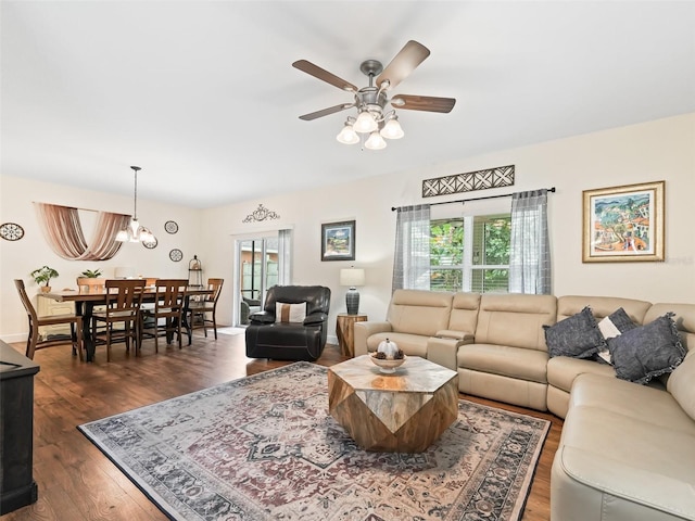 living room with dark wood-type flooring and ceiling fan with notable chandelier