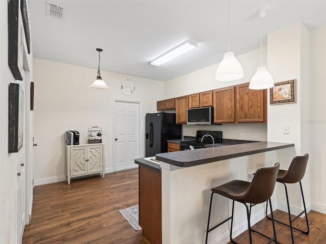 kitchen featuring a breakfast bar area, kitchen peninsula, black appliances, and decorative light fixtures