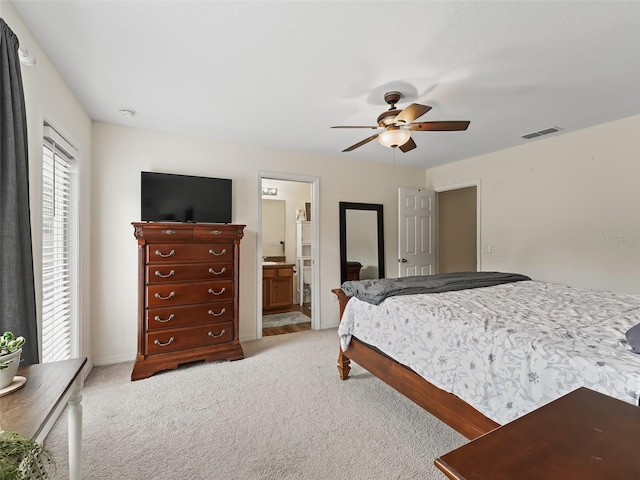 carpeted bedroom with ensuite bath and ceiling fan