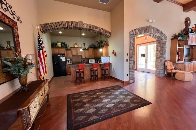 interior space with a high ceiling, dark hardwood / wood-style flooring, and beam ceiling