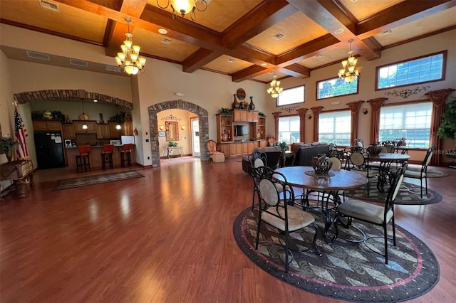 dining area featuring a towering ceiling, coffered ceiling, dark wood-type flooring, beam ceiling, and a chandelier