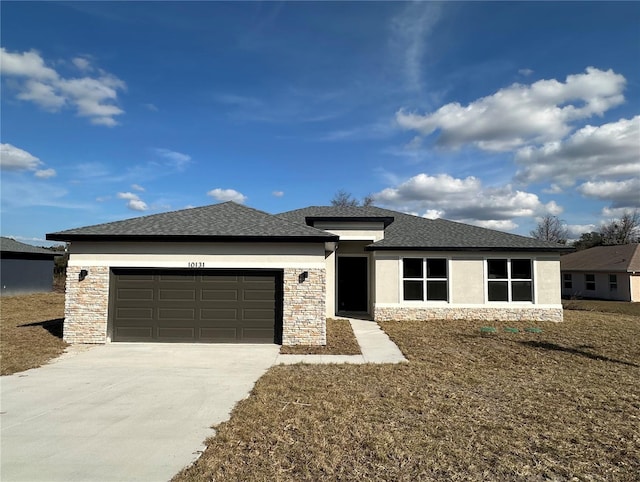 prairie-style home featuring stone siding, concrete driveway, a front lawn, and an attached garage