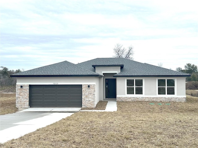 prairie-style house with a garage, stone siding, concrete driveway, stucco siding, and a front yard