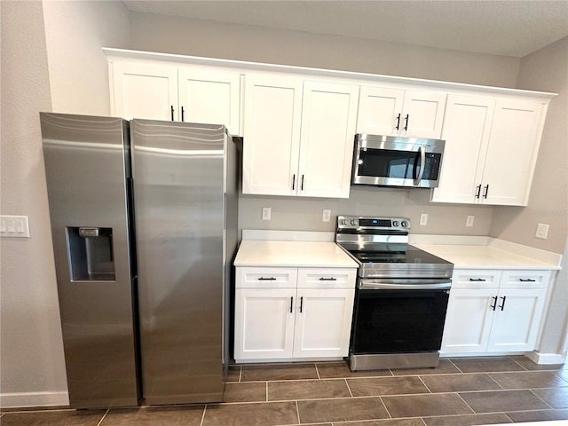 kitchen with light countertops, appliances with stainless steel finishes, white cabinetry, and baseboards