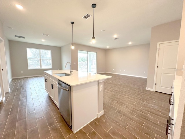 kitchen with a center island with sink, visible vents, hanging light fixtures, a sink, and stainless steel dishwasher