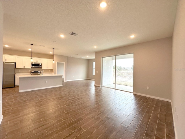 unfurnished living room featuring baseboards, visible vents, dark wood-type flooring, and recessed lighting