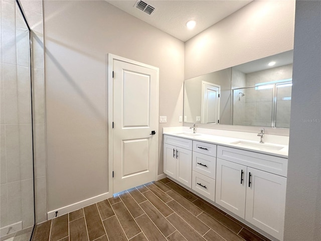 bathroom featuring wood finish floors, a sink, visible vents, and a stall shower