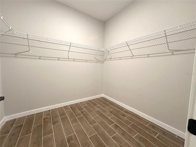 walk in closet with dark wood-style floors