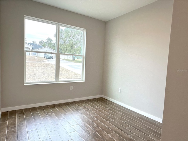 spare room with baseboards and dark wood finished floors