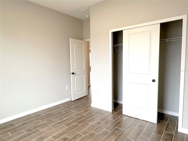 unfurnished bedroom with wood tiled floor, a closet, and baseboards