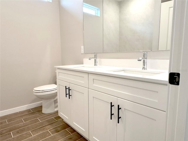 bathroom featuring wood finish floors, a sink, baseboards, and double vanity