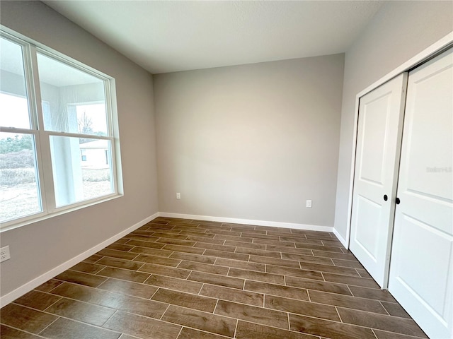 unfurnished bedroom with wood finish floors, a closet, and baseboards