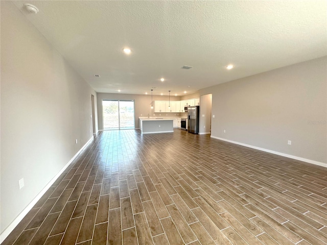 unfurnished living room with visible vents, baseboards, dark wood finished floors, and a textured ceiling