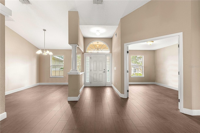 entryway featuring visible vents, baseboards, a notable chandelier, decorative columns, and dark wood-style floors