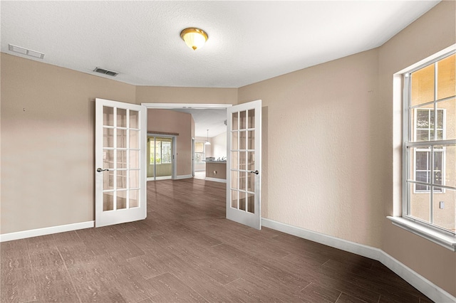 spare room featuring french doors, baseboards, wood finished floors, and visible vents