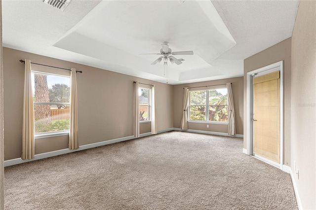 carpeted empty room featuring ceiling fan, a textured ceiling, and a tray ceiling