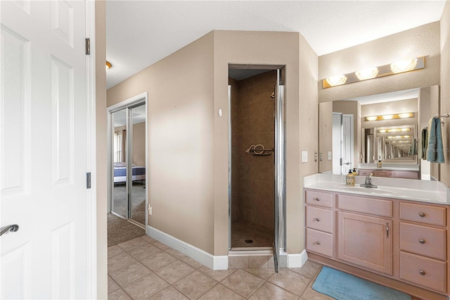 bathroom featuring tile patterned flooring, a shower with shower door, vanity, and a textured ceiling