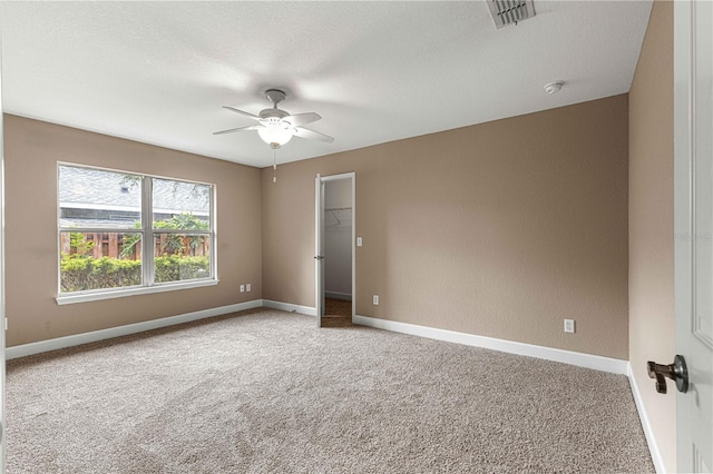 empty room featuring carpet, visible vents, baseboards, and ceiling fan
