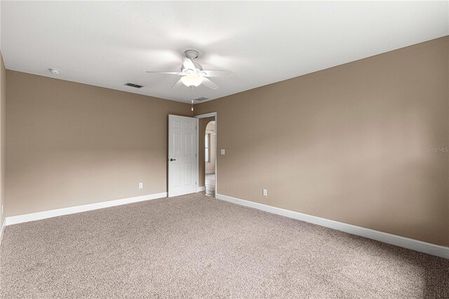 empty room with carpet flooring, visible vents, baseboards, and a ceiling fan