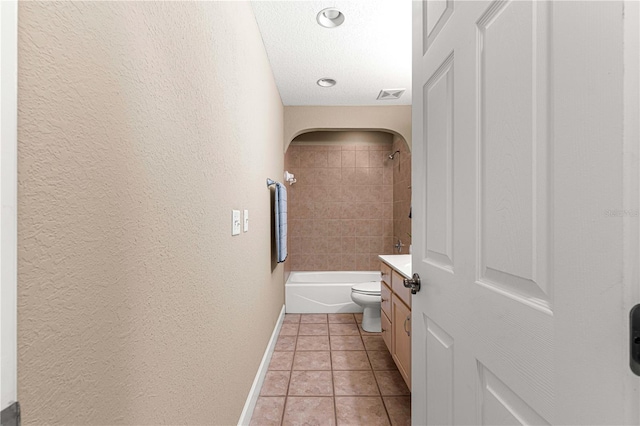 full bathroom with tiled shower / bath, vanity, a textured ceiling, toilet, and tile patterned floors