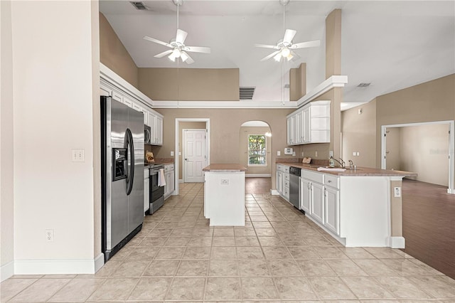 kitchen featuring light tile patterned floors, a kitchen island, high vaulted ceiling, white cabinetry, and appliances with stainless steel finishes